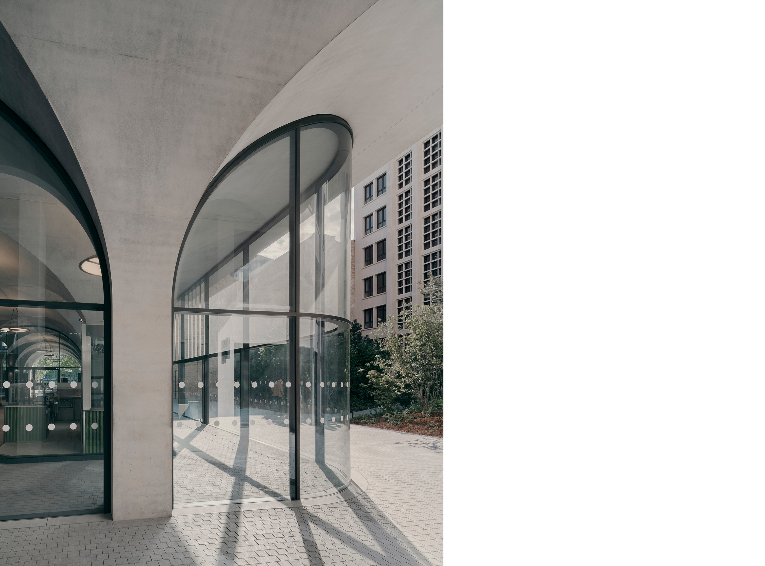 Curved glazed façade beneath the vaulted arcade facing the courtyard.