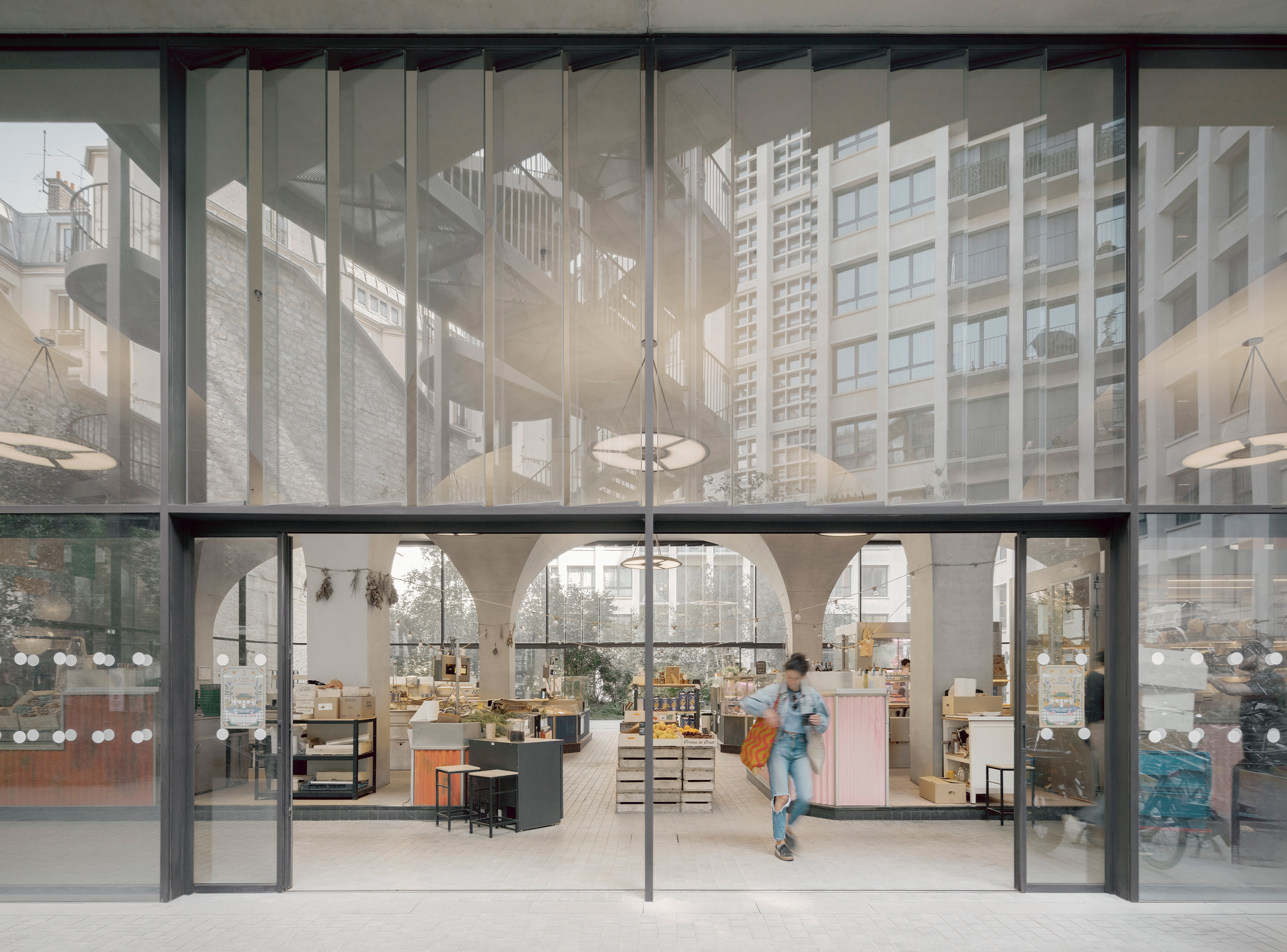 Covered market opening onto a landscaped courtyard beneath the vaulted arcade.