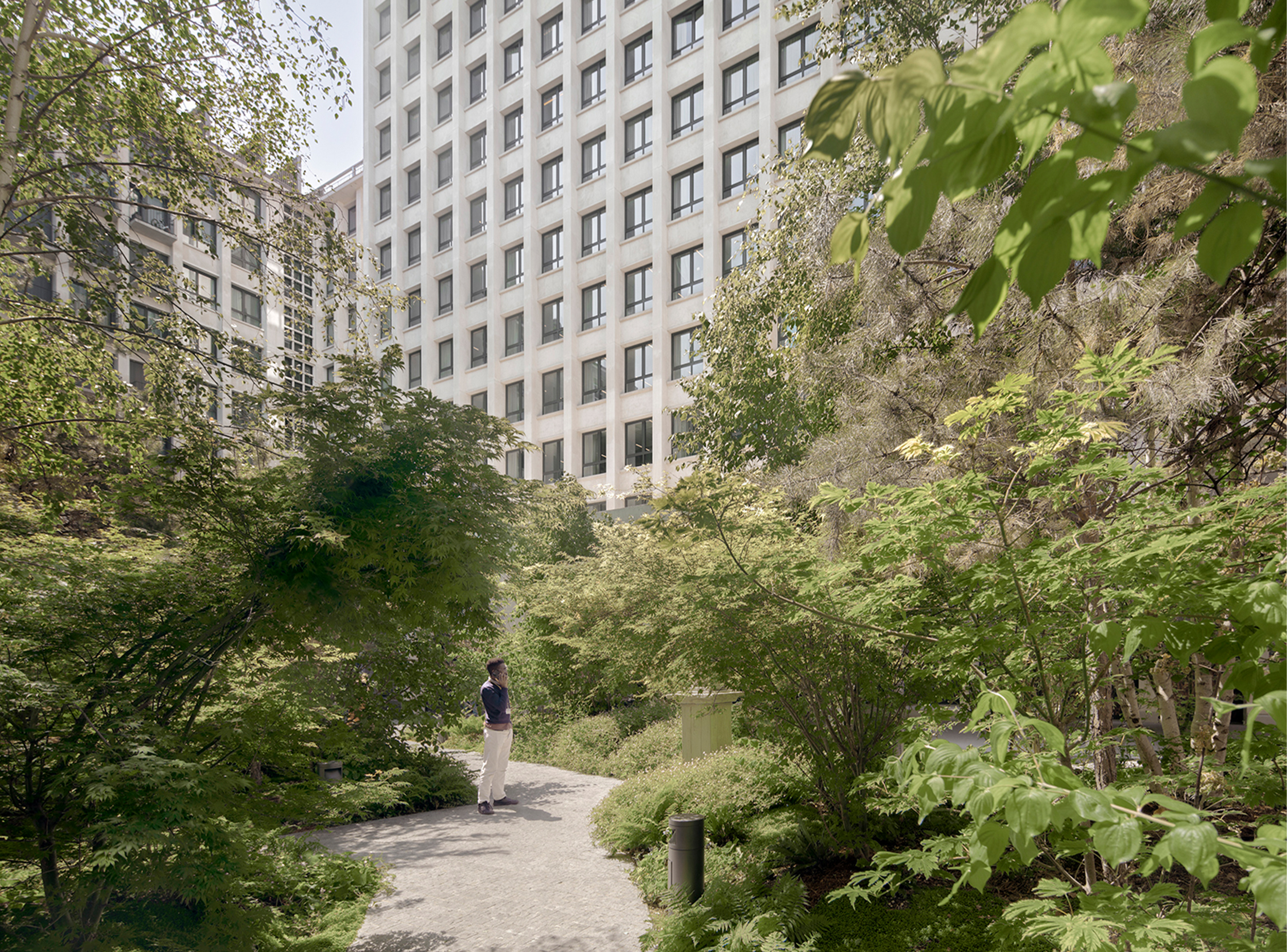 Garden courtyard at Morland Mixité Capitale, where dense planting and winding paths create a sheltered landscape within the transformed mixed-use development, bringing nature into the heart of the urban block.