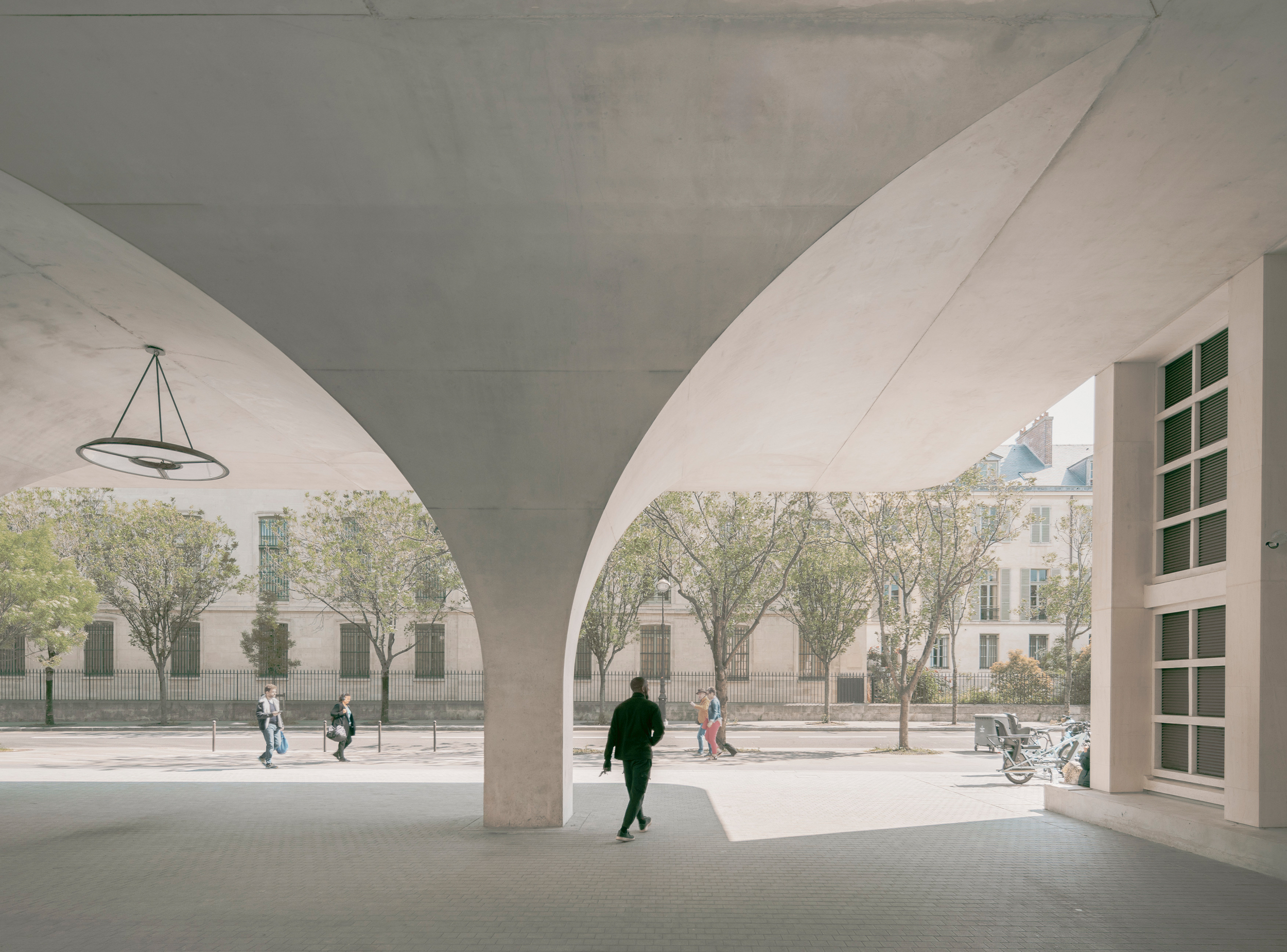 Vaulted arcade mediating between the urban boulevard and the landscaped courtyard.