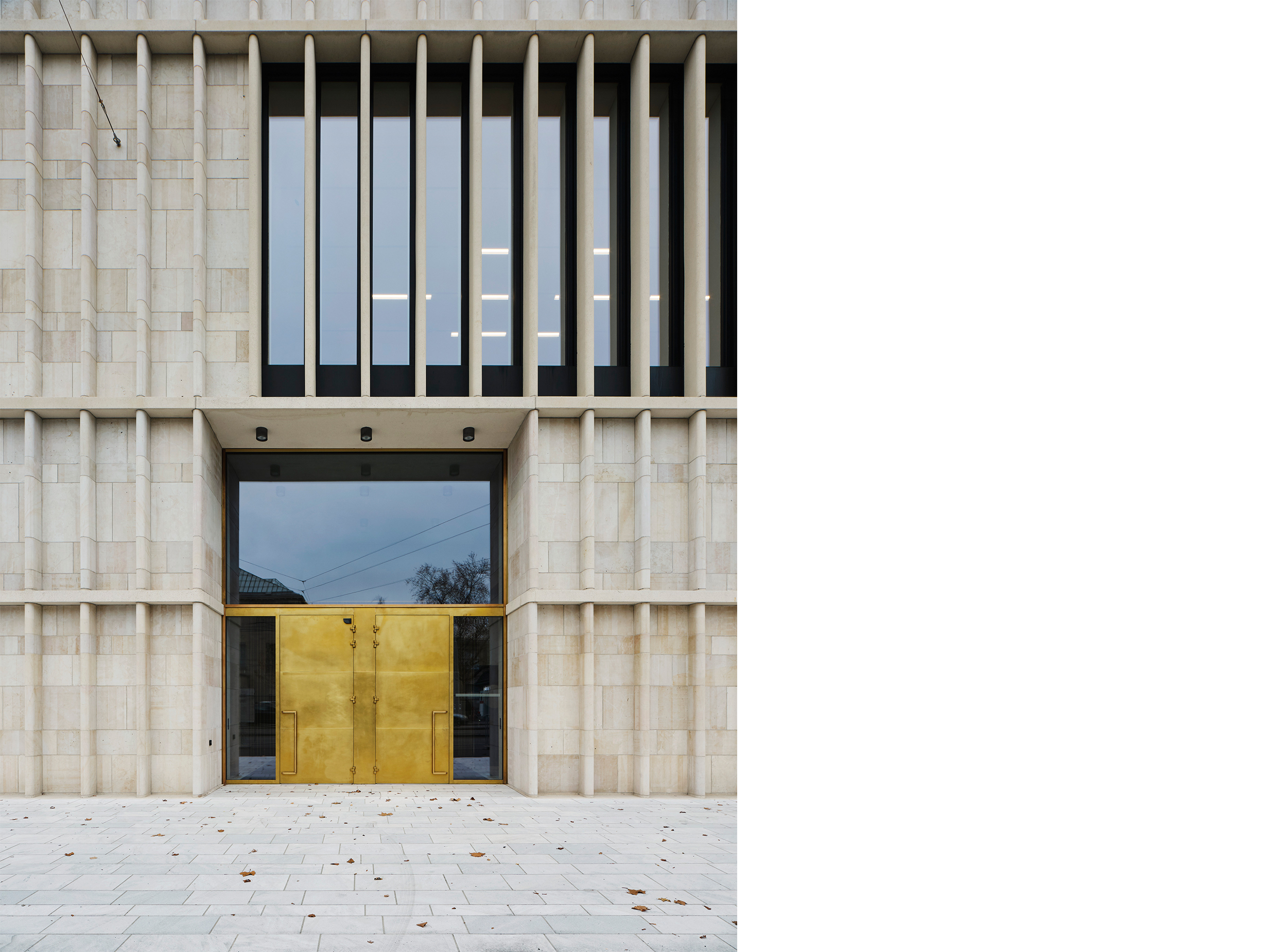 Close-up of the Kunsthaus Zürich Extension entrance, where brass doors, deep-set glazing and a finely detailed limestone façade establish a monumental yet inviting civic presence