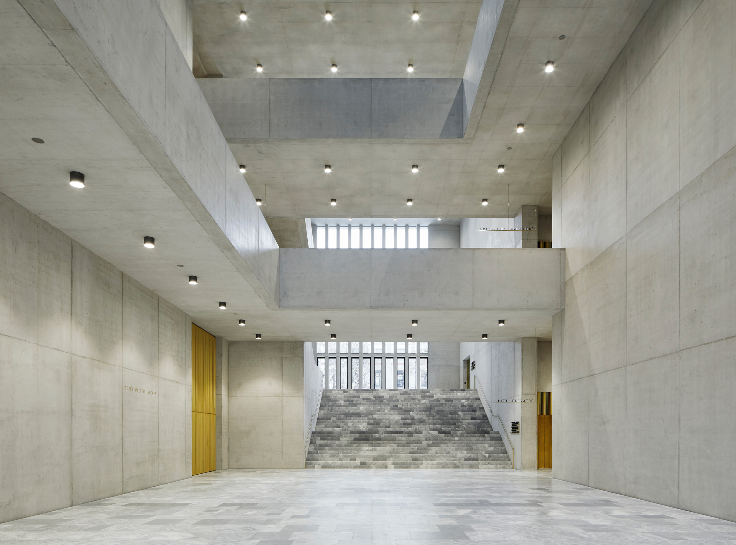 The central hall of the Kunsthaus Zürich Extension acts as the building’s primary public space, combining exposed concrete, natural stone and layered circulation to connect the museum’s galleries, entrances and civic functions.