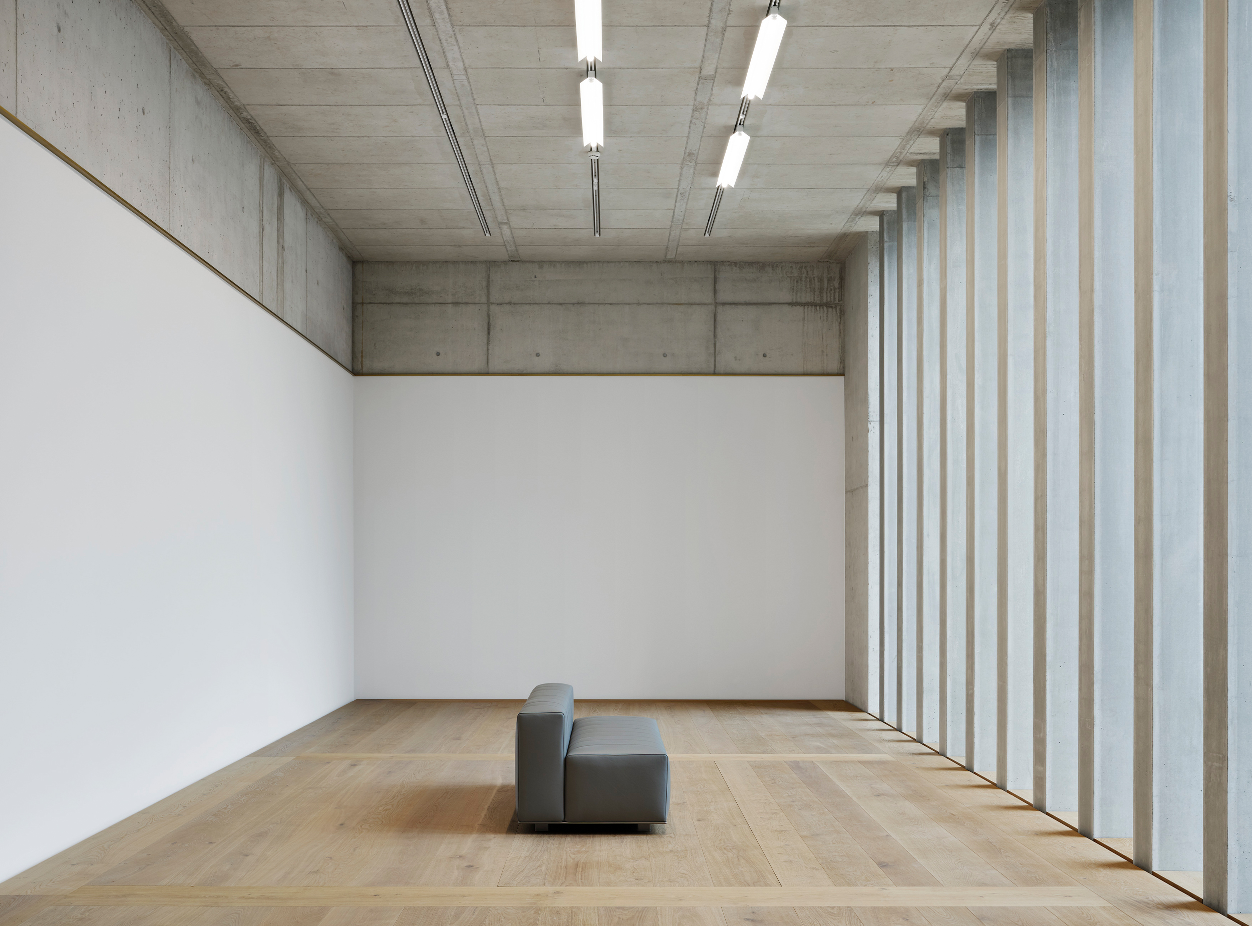 A gallery of the Kunsthaus Zürich Extension combines exposed concrete ceilings, timber floors and deep-set vertical windows to create a restrained exhibition environment shaped by natural light, proportion and material clarity.