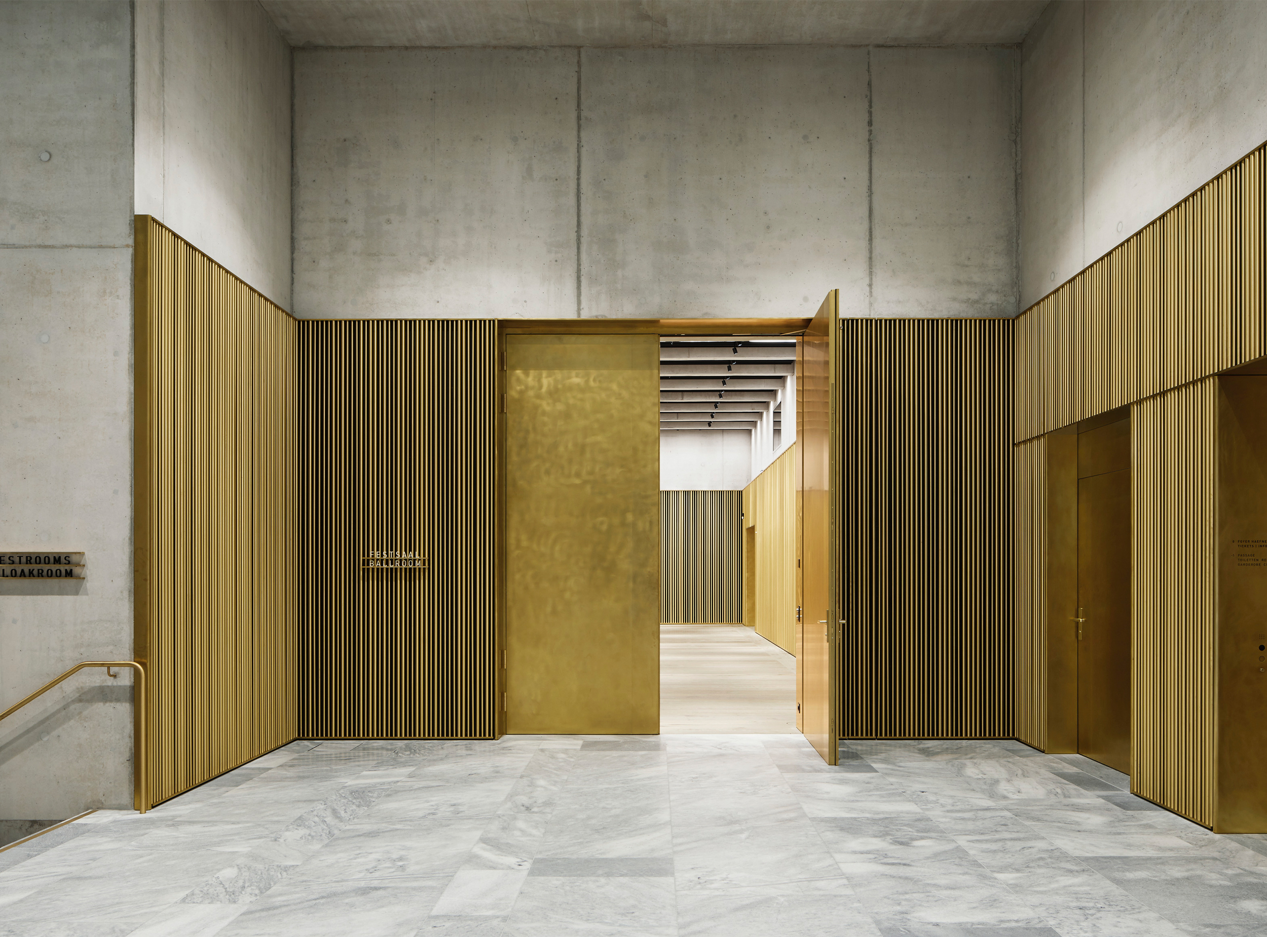 A brass-lined threshold within the Kunsthaus Zürich Extension combines finely detailed metal screens, exposed concrete and marble surfaces to create a carefully articulated sequence between the central hall and adjoining museum spaces.