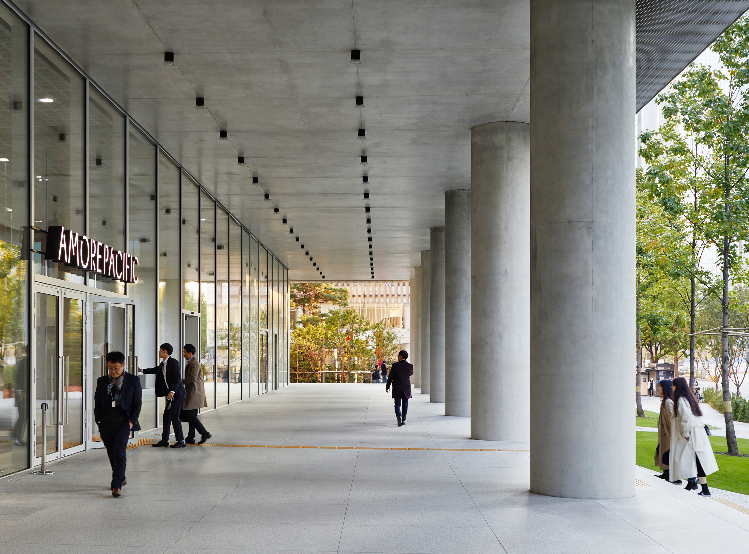 Entrance colonnade of the Amorepacific headquarters with large concrete columns, glazed façade and landscaped public realm.