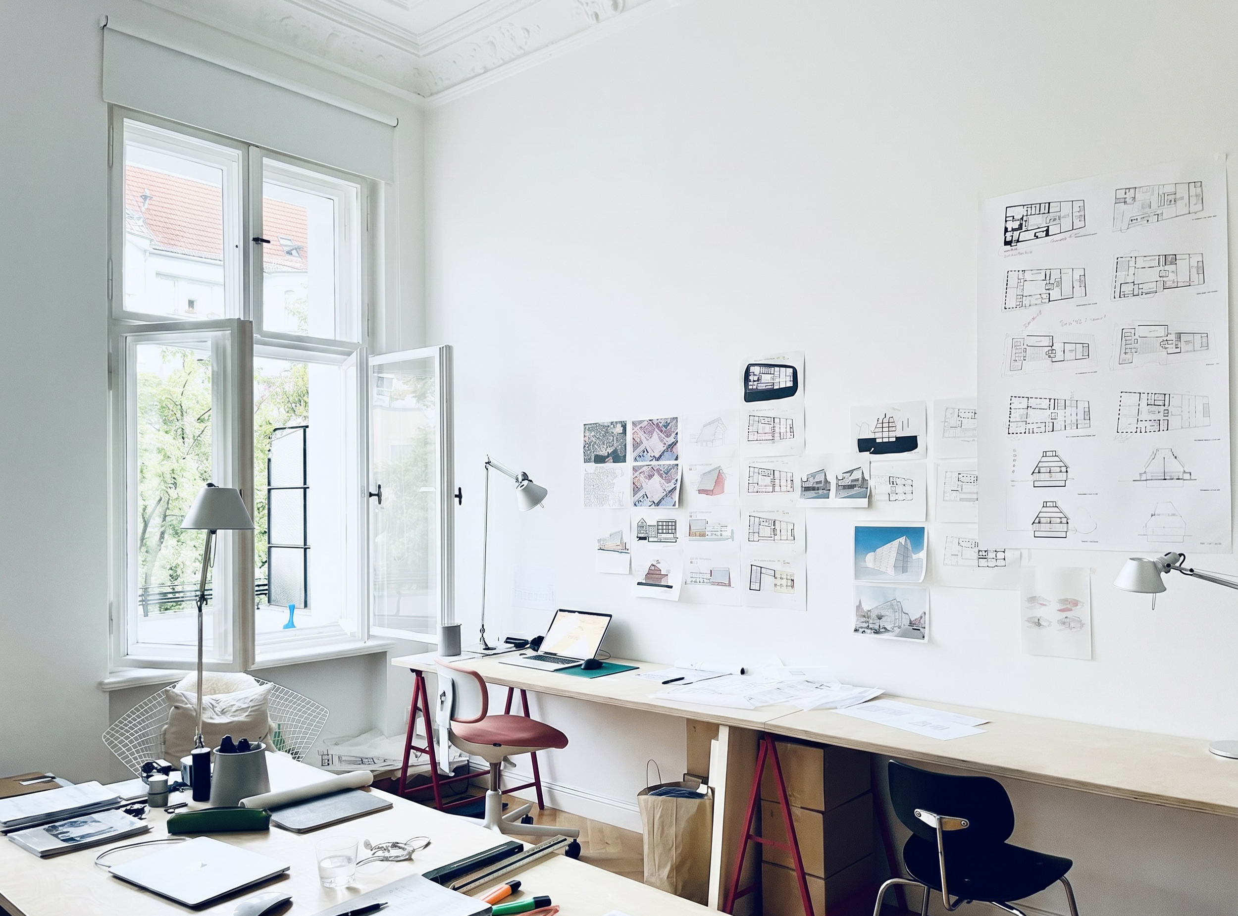 Architectural drawings and design studies pinned to a studio wall.